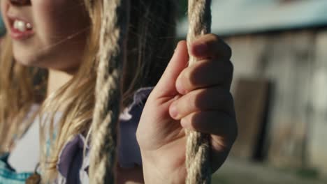 close up of little girl swinging in summer day.