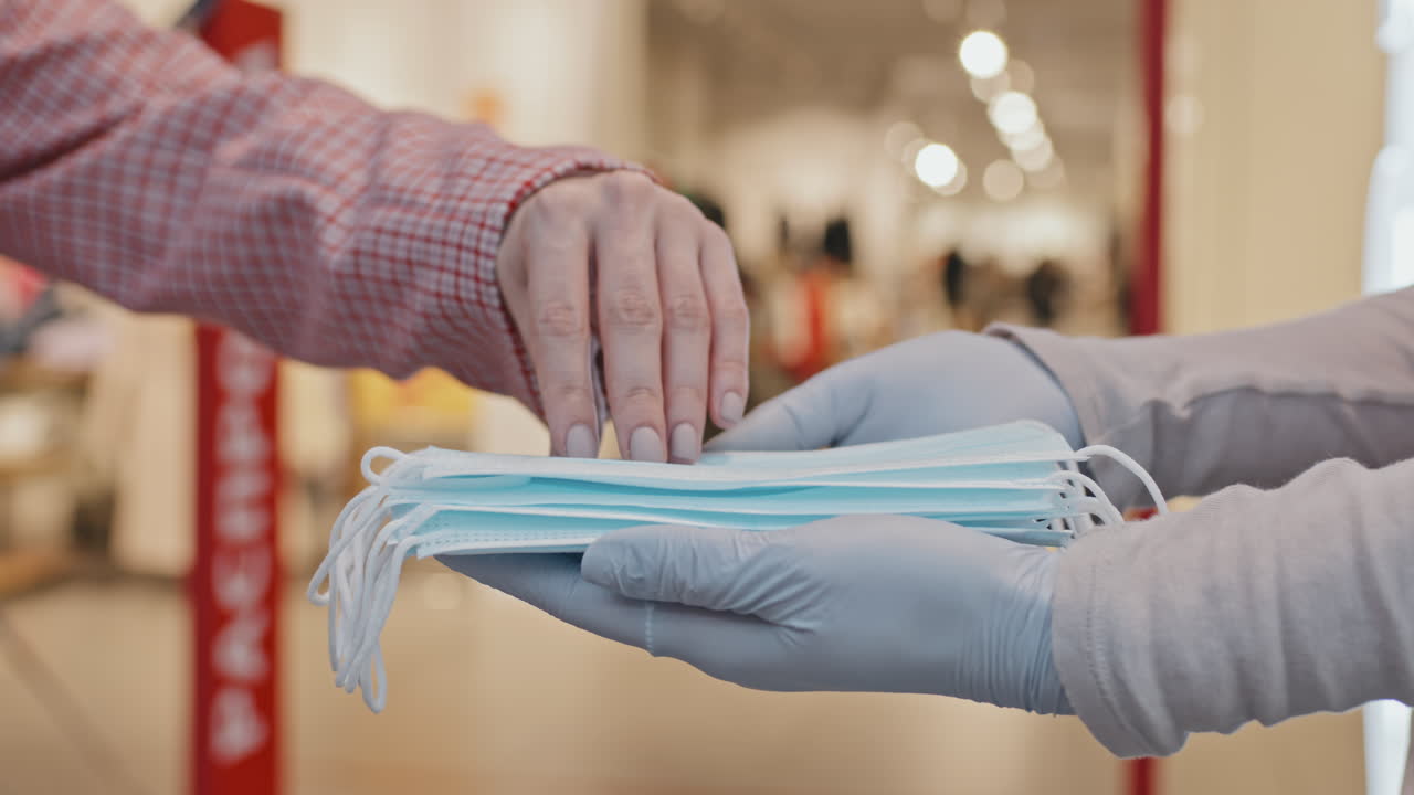Close-Up Of Customers Taking Face Masks Before Entering Clothing Store
