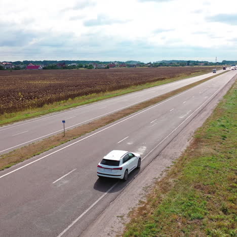 aerial view on white audi moving on the highway. top view of luxury car driving slowly on the background rural area at day time.