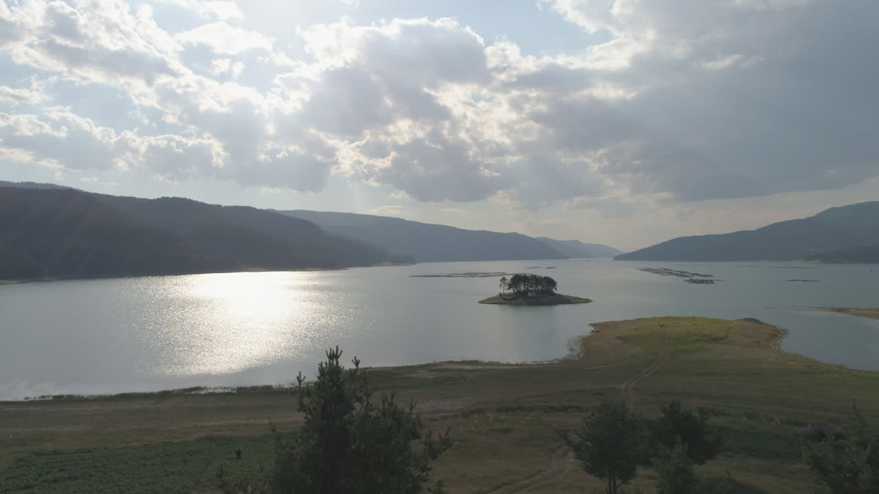 горная плотина с небольшим островком с деревом