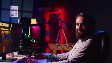 retrato de un hombre sonriente en la sala de estar oscura jugando videojuegos atractivos en la pc de juegos