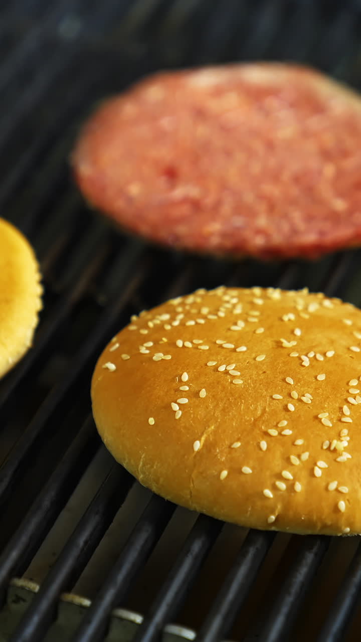 Cooking beef and pork patty for burger. Meat roasted with buns at kitchen grill. Selective video from above. Vertical video