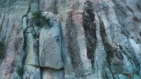 a tiny climber is stuck on a tricky step on a granite wall