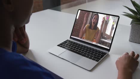 African-american-woman-talking-on-video-call-on-laptop-with-female-office-colleague-at-home