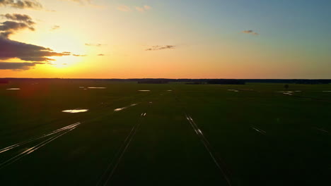 aerial drone shot over train tracks passing along barren plains with sun setting in the background