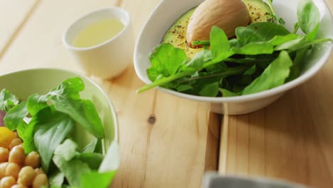 video of bowls of fresh salad with green leaves on wooden background