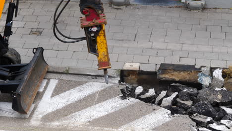 high angle static shot of hydraulic breaker breaking asphalt