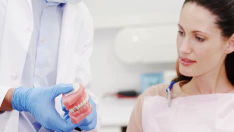 dentista mostrando dientes de modelo al paciente