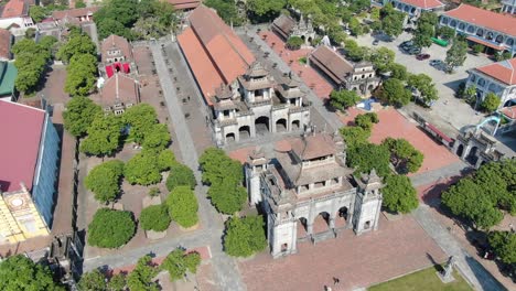 drone aerial view in vietnam circling around over a stone temple in ninh binh on a town with brick roof buildings on a sunny day