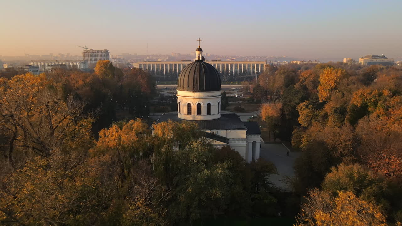 Aerial drone view of Chisinau in autumn at sunset, Moldova. Central park with yellowed trees and people, Cathedral, slow motion