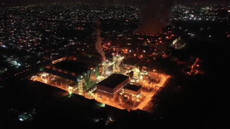 Aerial-shot-of-a-working-factory-in-the-middle-of-a-Mexican-town-a-few-hours-before-sunrise