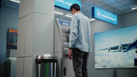man using atm in airport