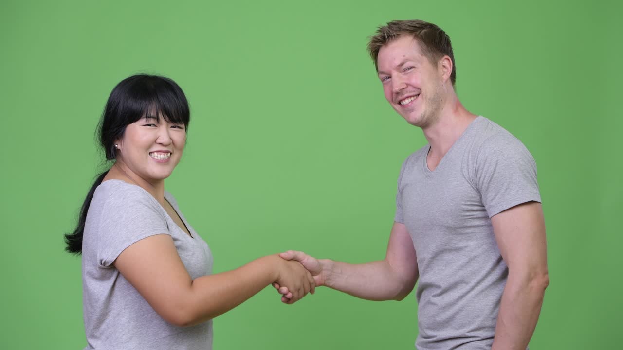 젊은 다민족 커플이 서로 손을 흔들고 있습니다.