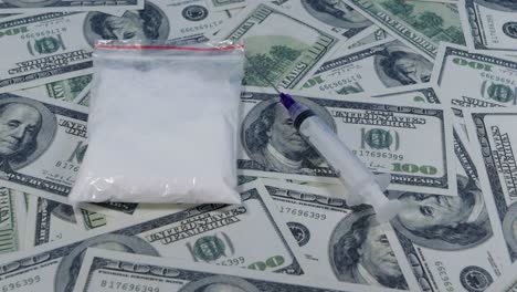 disparo de deslizamiento lento sobre drogas y jeringas sobre cientos de billetes de dólares estadounidenses