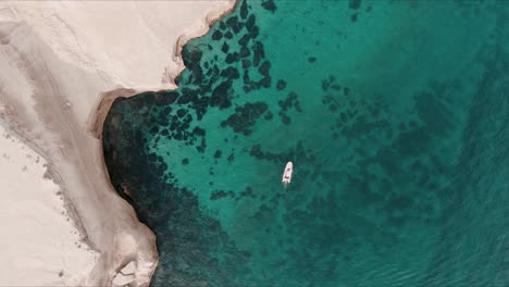 boat moving next to a cliff in patagonia from a drone top shot slowmotion