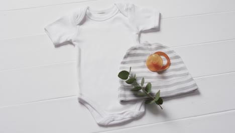 video of white baby grow, hat and dummy with copy space on white background