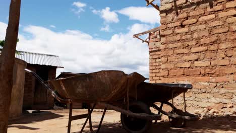 cerca de dos carretillas oxidadas fuera de la casa con paredes de ladrillo rojo