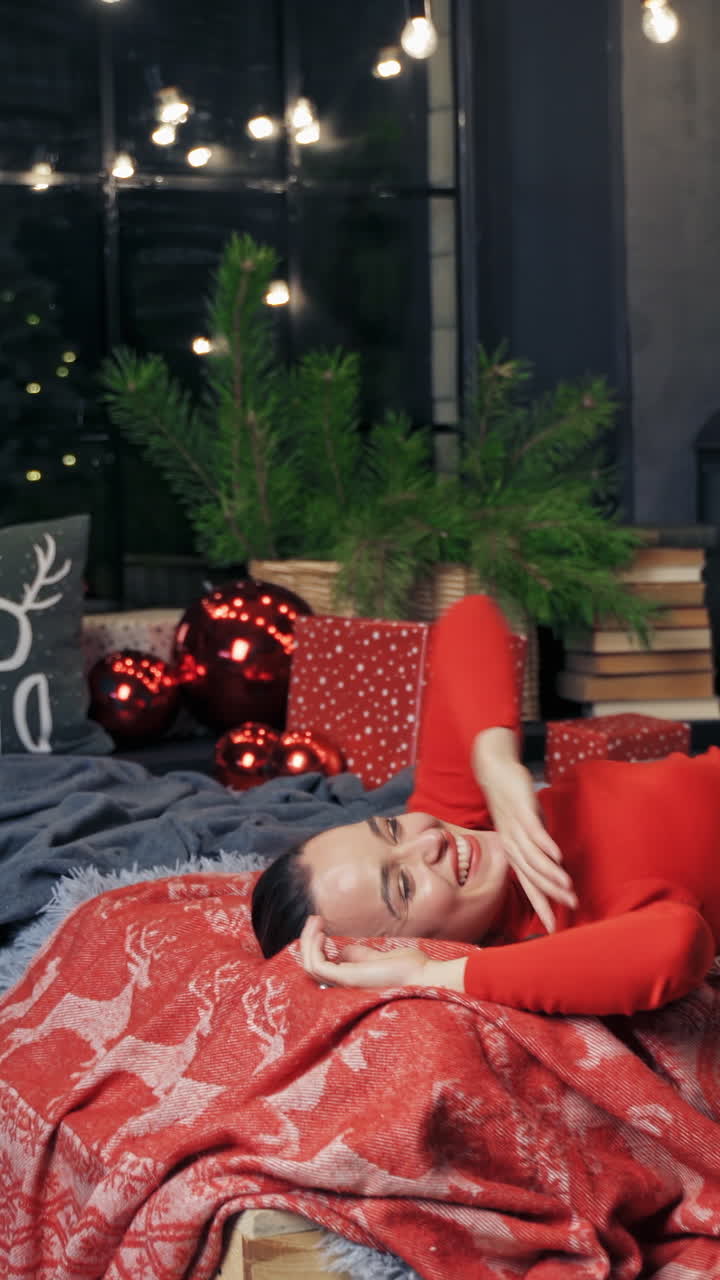 Happy woman relaxing in bed. Woman lying on bed with Christmas decorations
