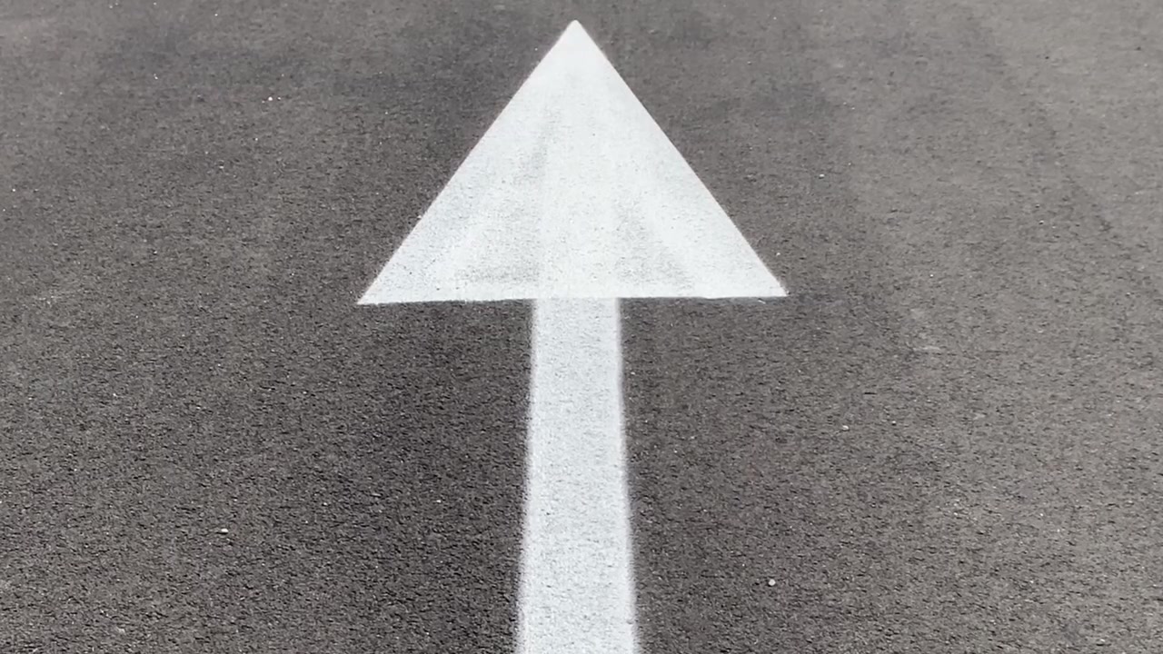 Weißer Pfeil auf Asphaltstraße, vorwärtsweisend. Konzept für zukünftiges Wachstum, Motivation zur persönlichen Entwicklung und geschäftlichen Fortschritt.