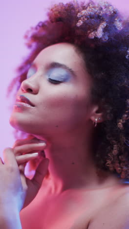 vertical video of biracial woman with dark hair in blue and pink light, slow motion