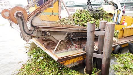 barco quitando escombros de la superficie del río bangkok