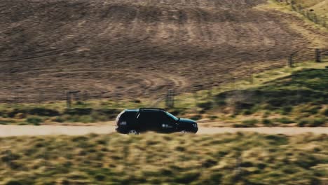 a jeep driving through a landscape in argentina on a sunny day with clouds in the sky