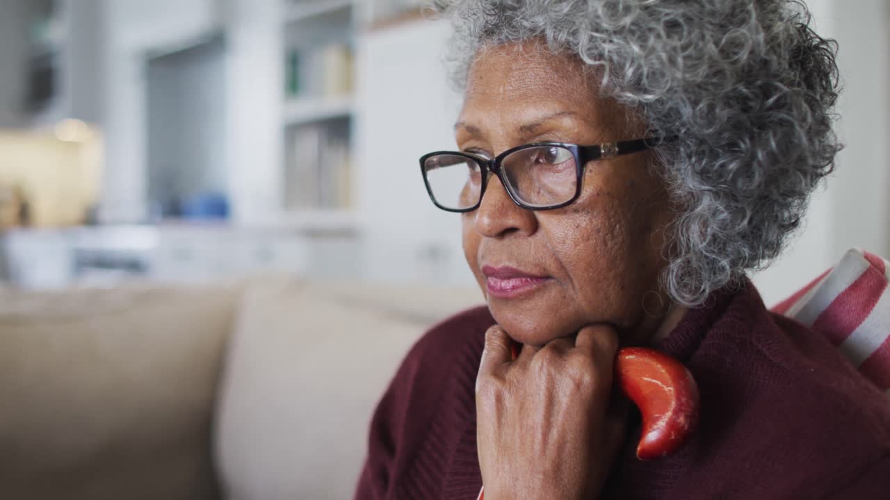 Thoughtful senior african american woman holding walking stick sitting on the couch at home