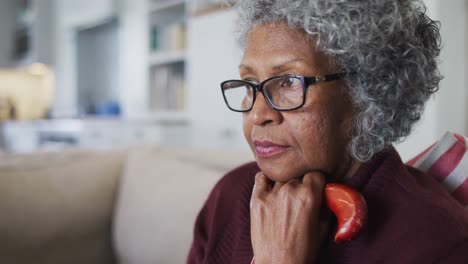 thoughtful senior african american woman holding walking stick sitting on the couch at home