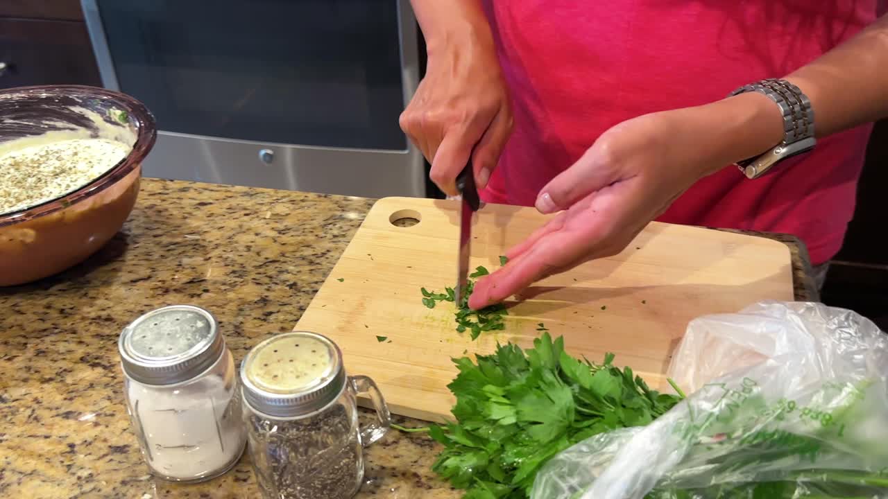 Woman's hands seen chopping parsley for a homemade meal