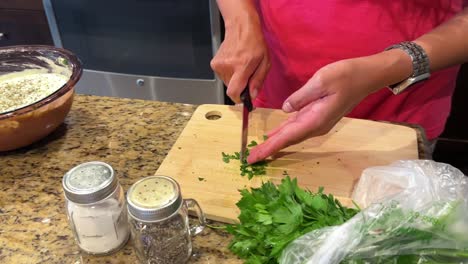 woman's hands seen chopping parsley for a homemade meal