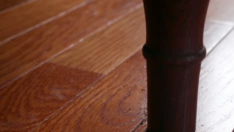 close up shot of a bedpost scratching a hardwood floor as the bed is being shaken suggestively from activity above