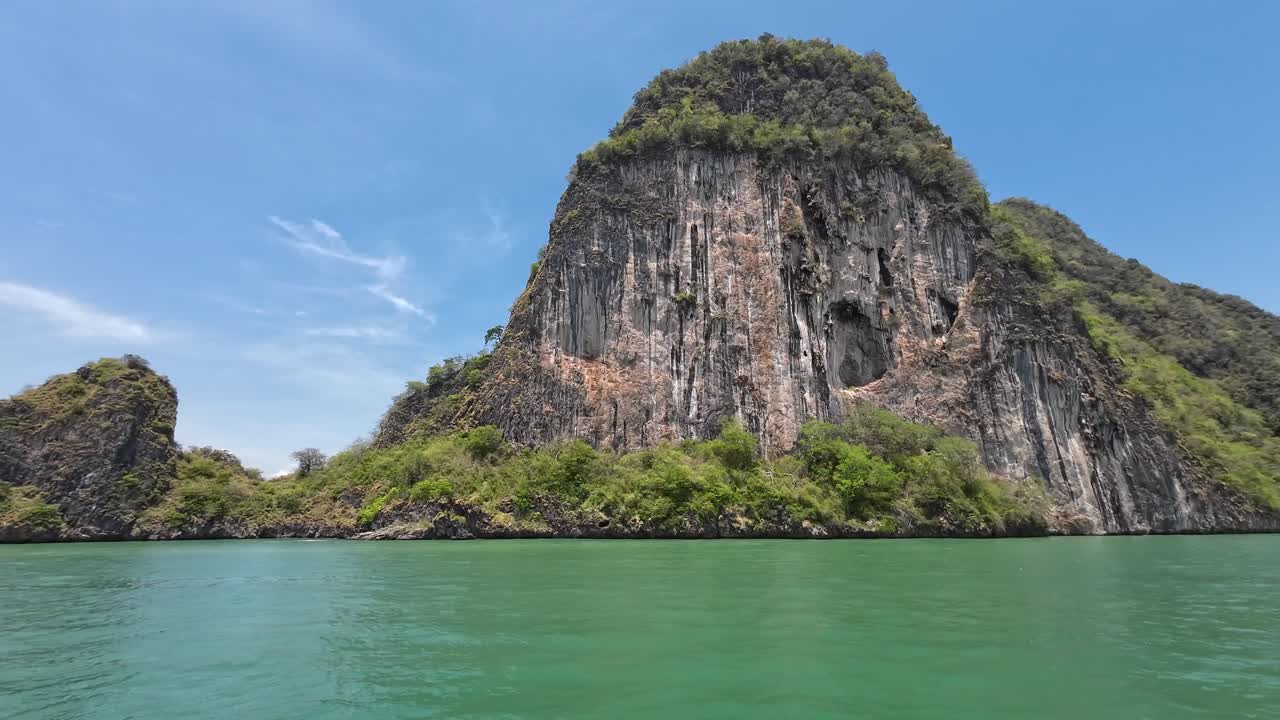 A scenic boat ride through towering limestone cliffs in Phang Nga Bay, Phuket, Thailand, featuring tropical waters, dramatic karst formations, and a popular travel destination