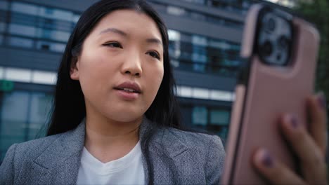 business chinese woman having video call next to the building