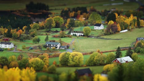 a scenic village with homes and farmlands, framed by the warm tones of autumn in a serene countryside