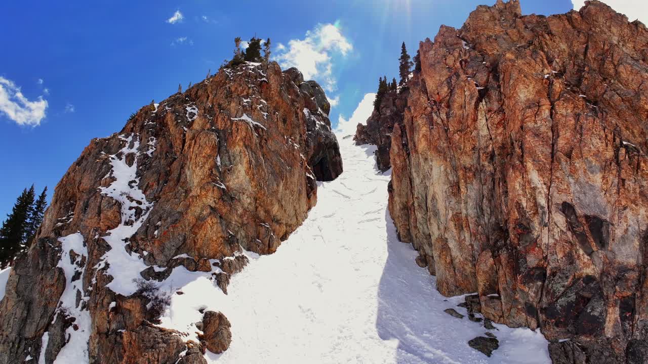Spring cornice rock walls chute Deer Creek Trail Montezuma winter Rocky Mountain Colorado avalanche terrain aerial drone sunny blue sky deep powder snow snowmobile ski snowboard backcountry forward up