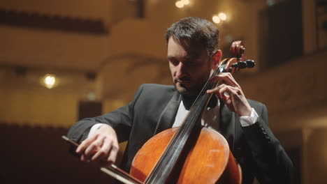 el violonchelista está tocando un viejo violonchelo retrato del violonchalista en la escena de la orquesta sinfónica de la ópera