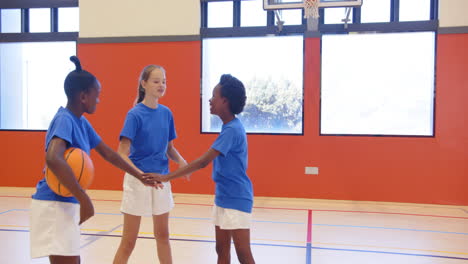 playing basketball, three school girls in gym shaking hands, wearing blue shirts, copy space