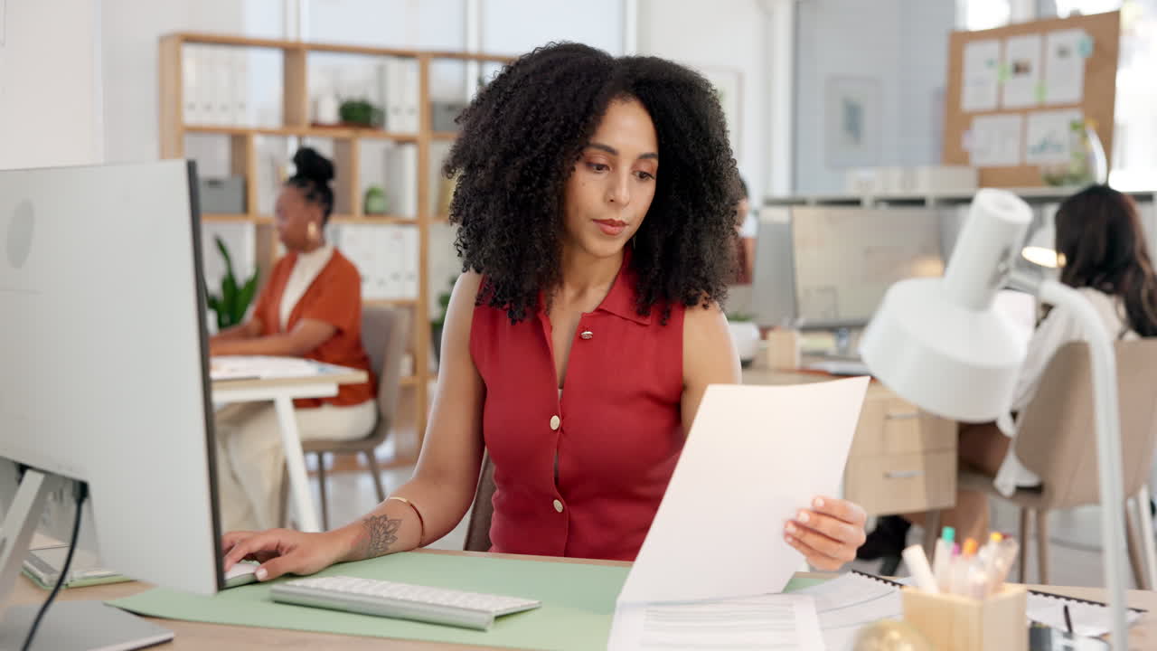 Imprenditrice concentrata che lavora al computer e rivede documenti in ufficio