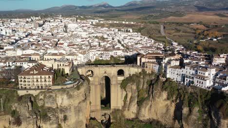 Town-of-Ronda-Spain-in-the-province-of-Málaga-with-Puente-Nuevo-arch-bridge-joining-the-village,-Aerial-pan-right-circling-shot