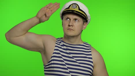 young sailor man salutes with hand, looking up. seaman guy in sailor's vests