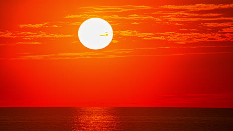 Time lapse shot of red fired sky during sunset behind tranquil ocean water in the evening