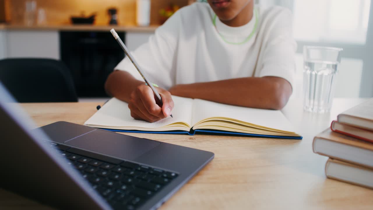 Student studying at home with laptop and notebook