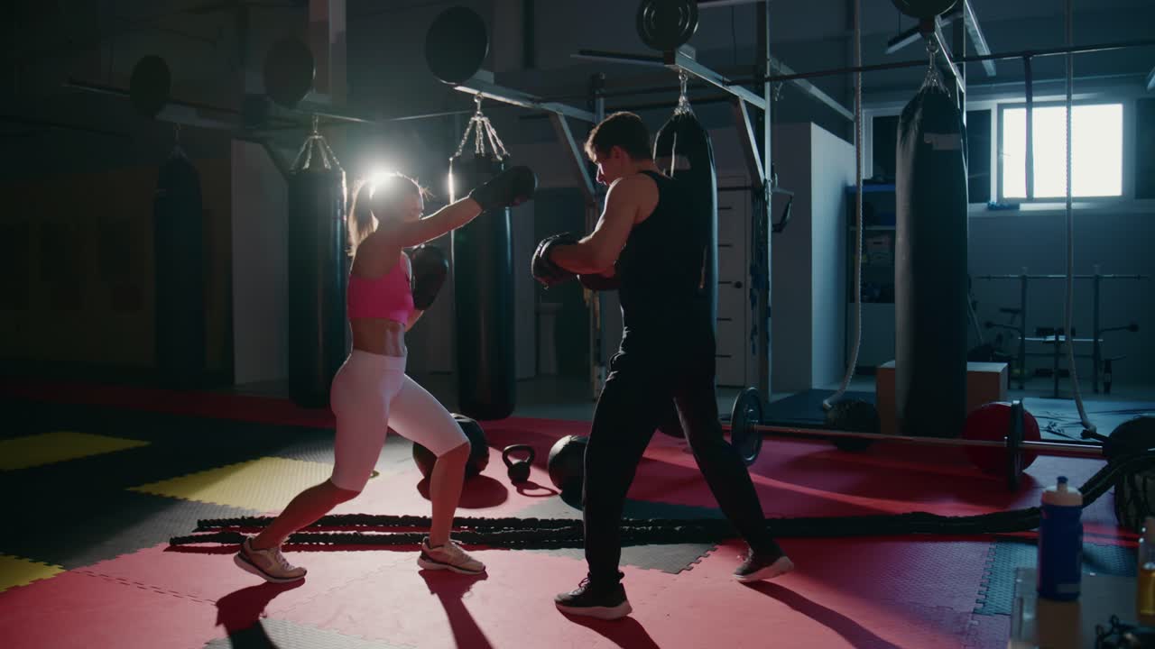 Mulher e Homem Treinando Boxe em uma Academia Escura
