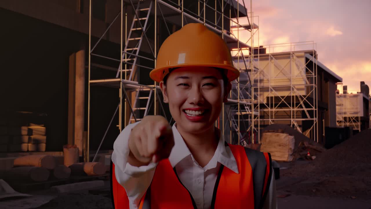Close Up Of Asian Female Engineer With Safety Helmet Smiling And Touching Her Chest Then Pointing At You While Standing At Construction Site in Progress to New House