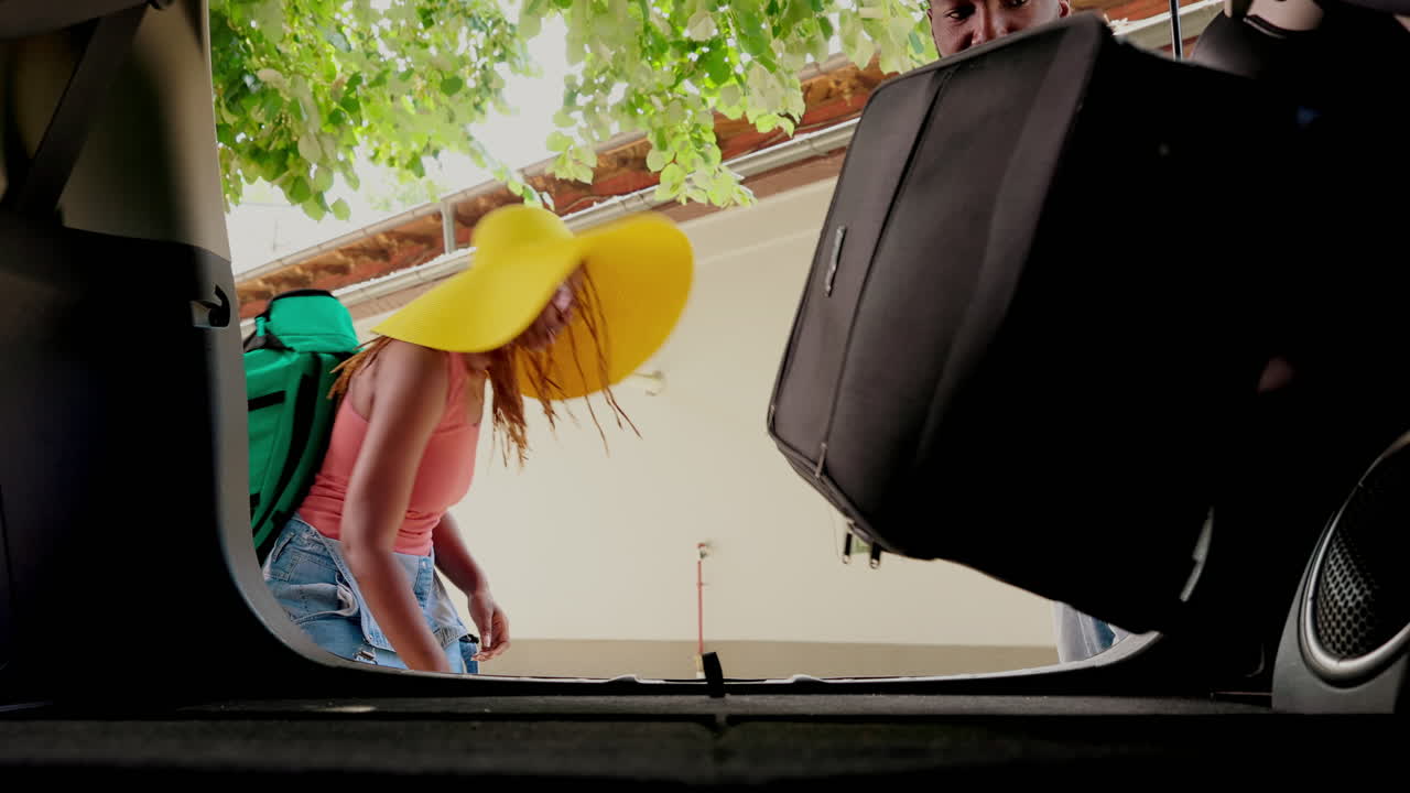 Couple packing luggage into car trunk for vacation