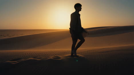 Silhouette of a Man Walking on Sand Dunes at Sunset