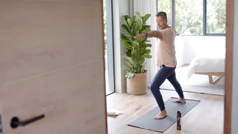 hombre de dos razas que hace ejercicio, practica yoga en casa.