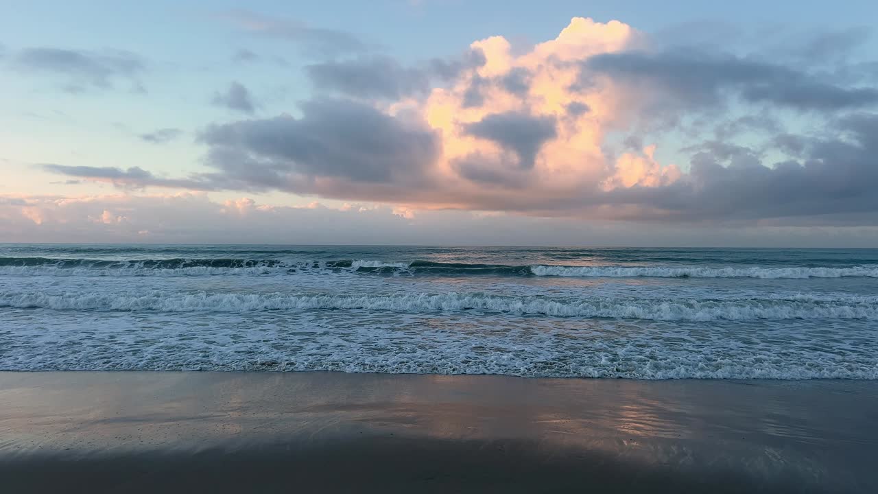 View of waves breaking on the shore under a cloudy sky. Ground Level