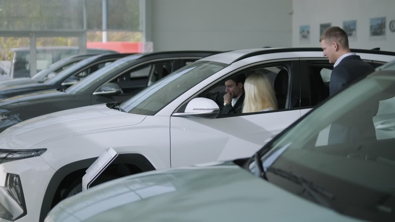 Couple Looking at New Cars in Dealership with Salesman