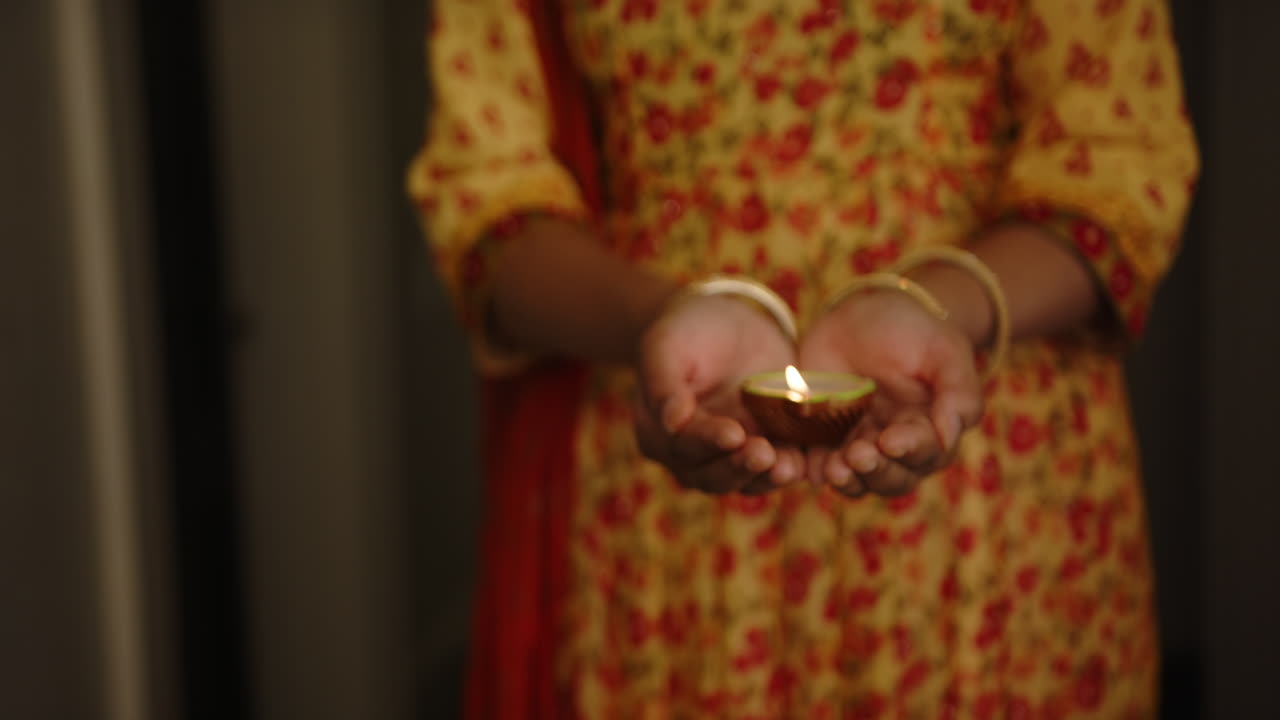 Holding lit diya, Indian woman in traditional sari celebrating festival of lights